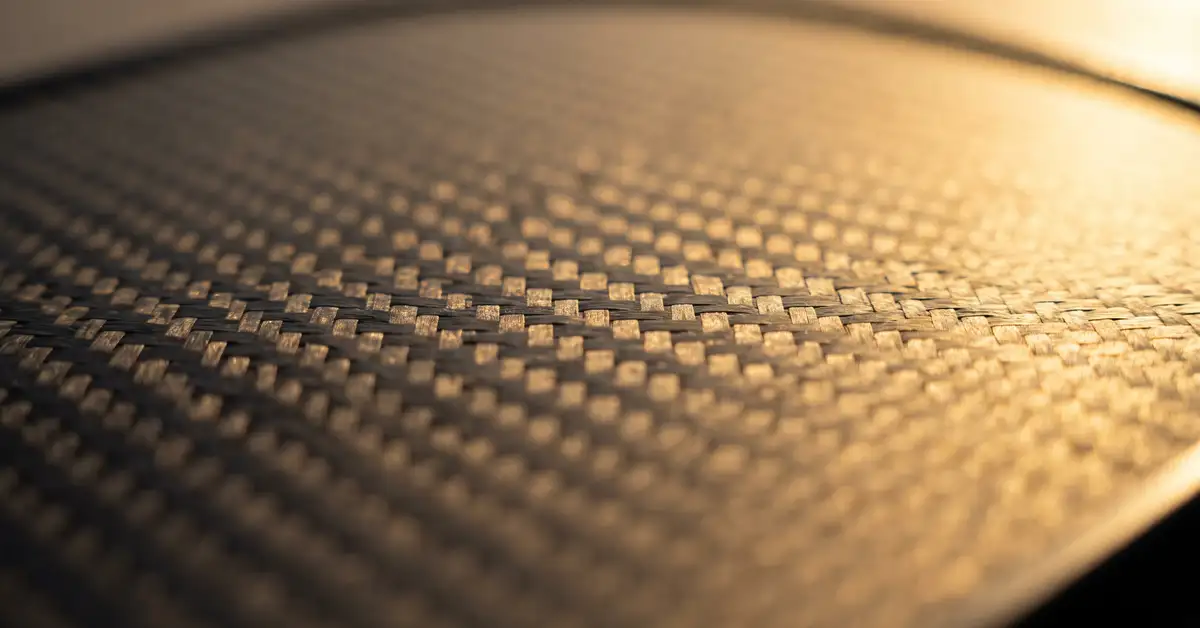 Close-up abstract macro photograph of a pickleball paddle face texture with warm side lighting